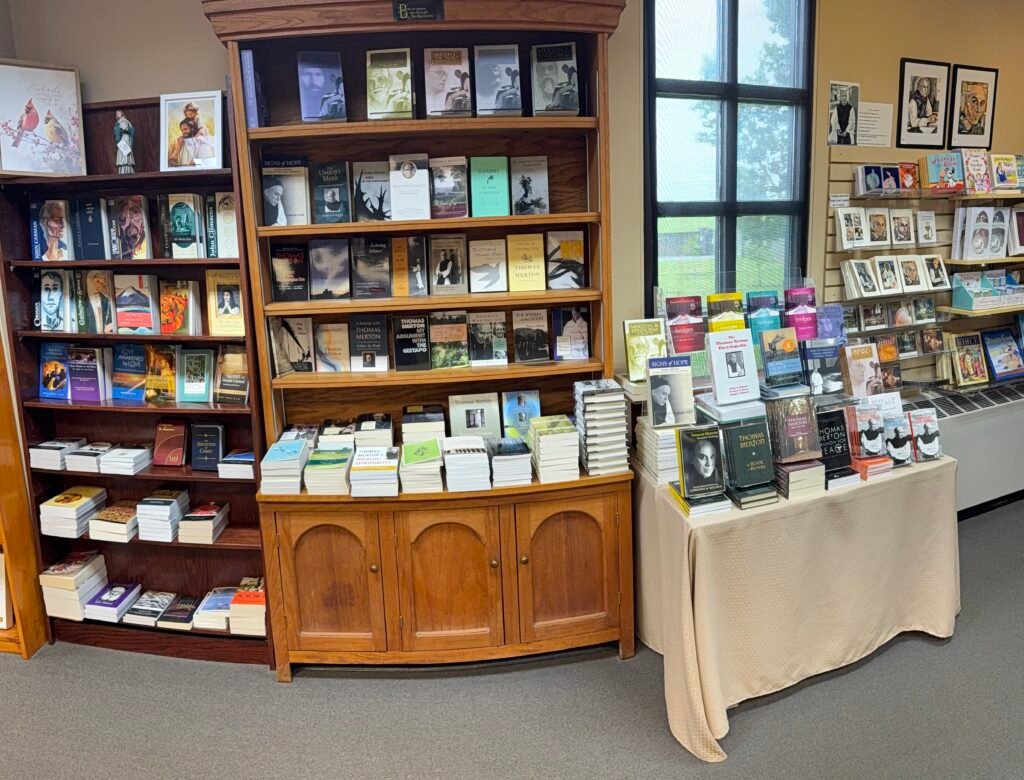 Bookshelf and table displaying Thomas Merton books and biographies in the gift shop