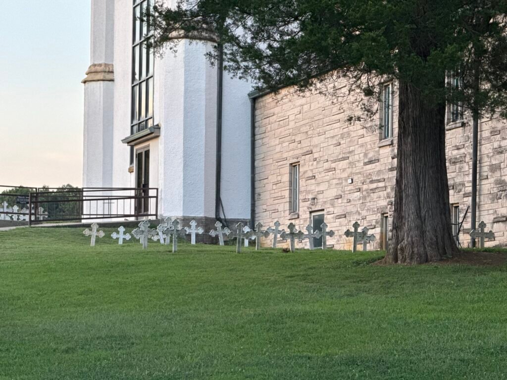 Distant view of path to Merton grave marker near large tree just outside retreating dining area and garden