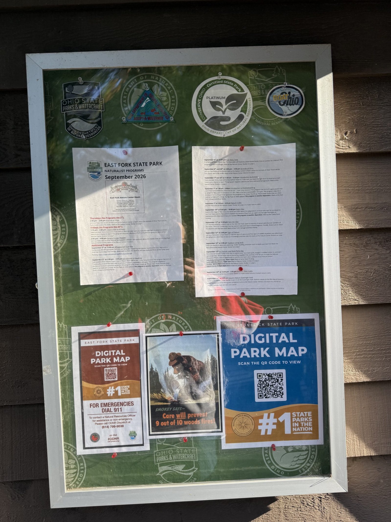A glass-fronted bulletin board holding the park's naturalist program schedule and park map notices