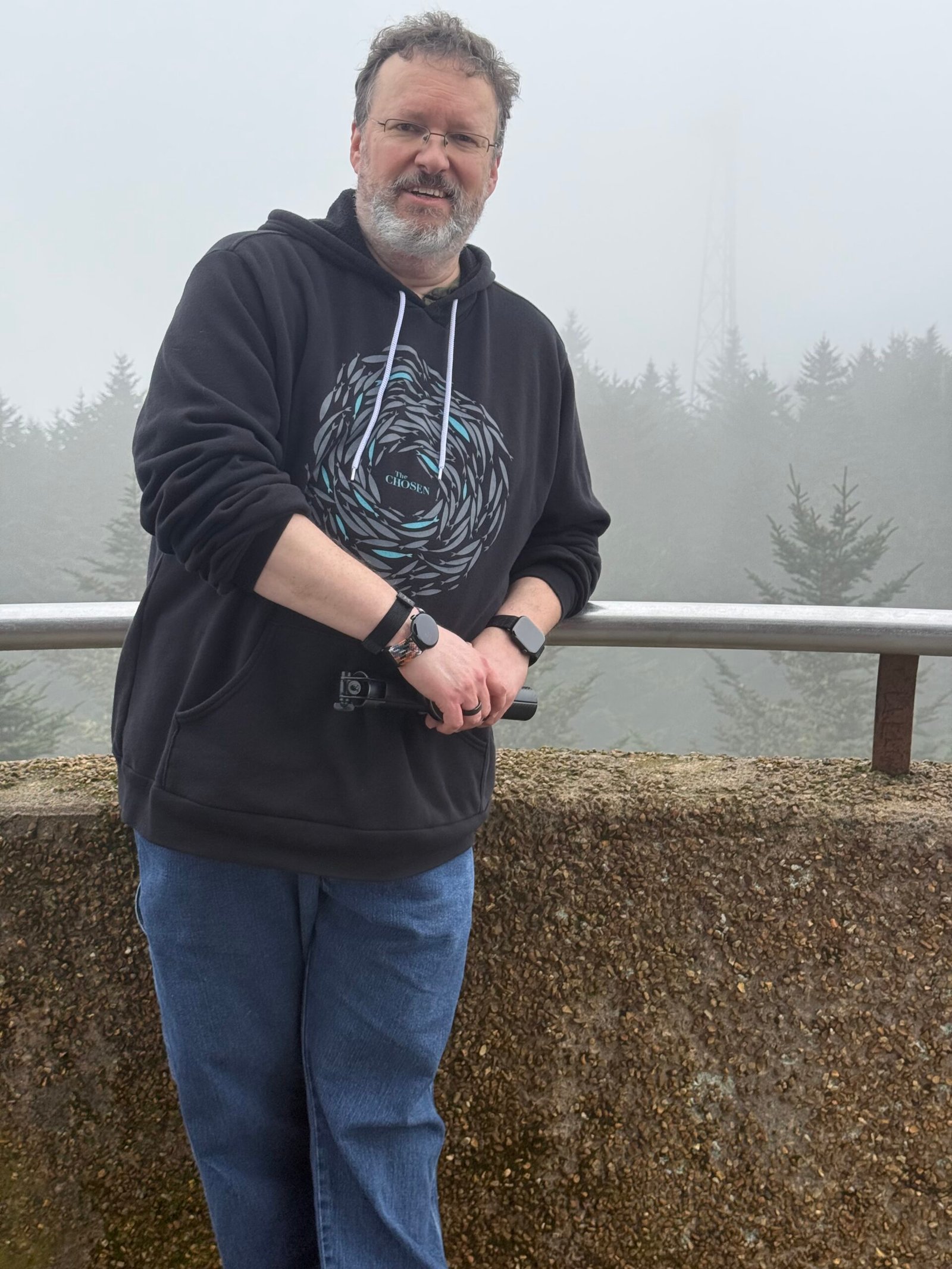 The author in a dark hoodie standing at a railing on the Kuwohi summit, with nothing but fog behind him